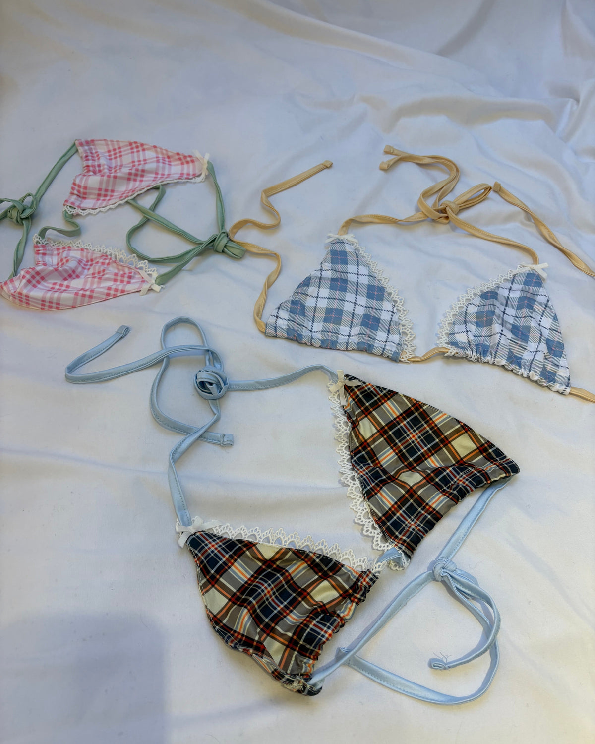 Plaid bikini sets on hangers against a white background