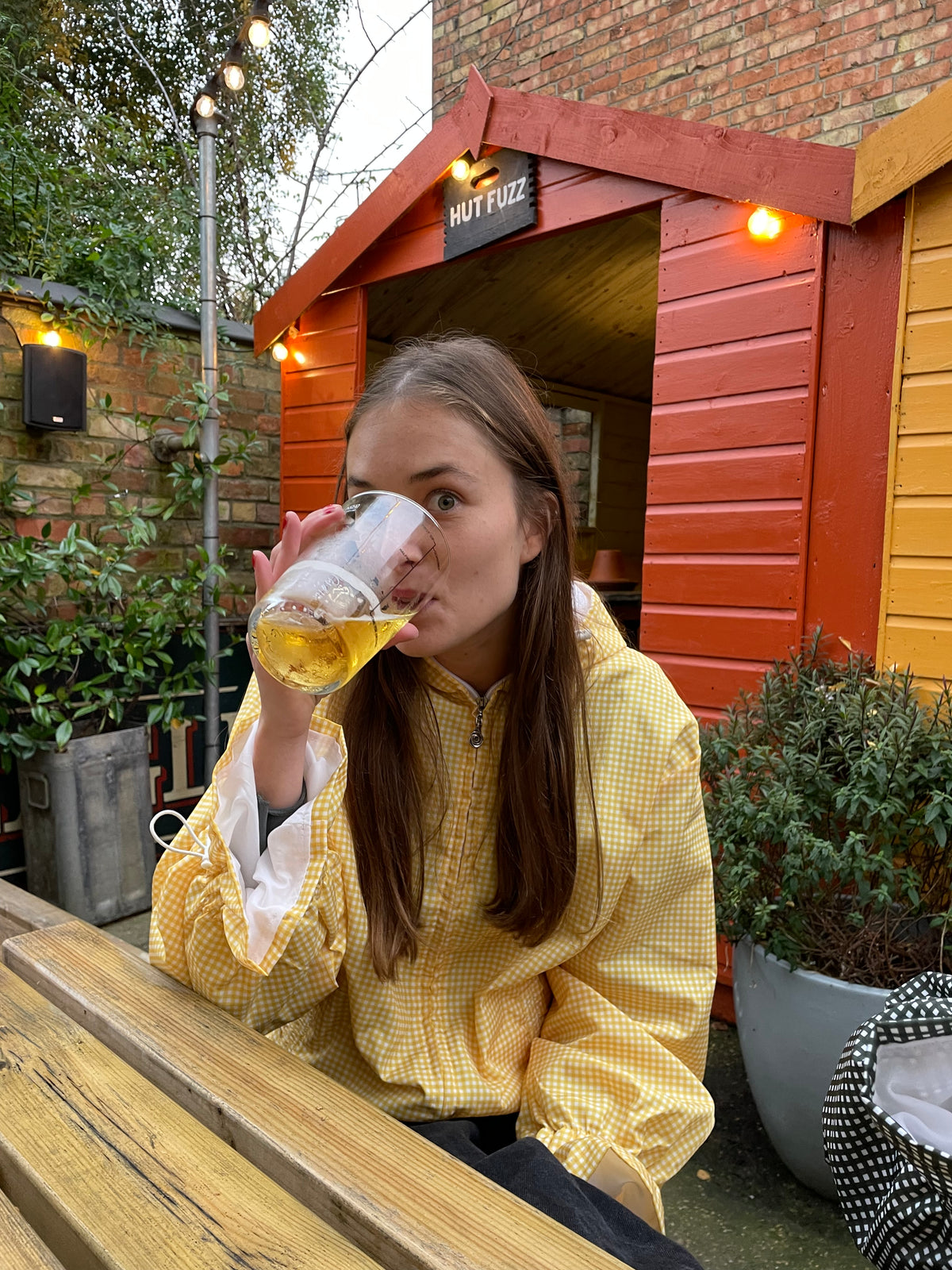 a woman drinking a beer wearing a yellow windbreaker
