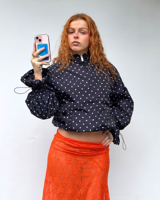 a woman wearing a navy and cream polka dot windbreaker