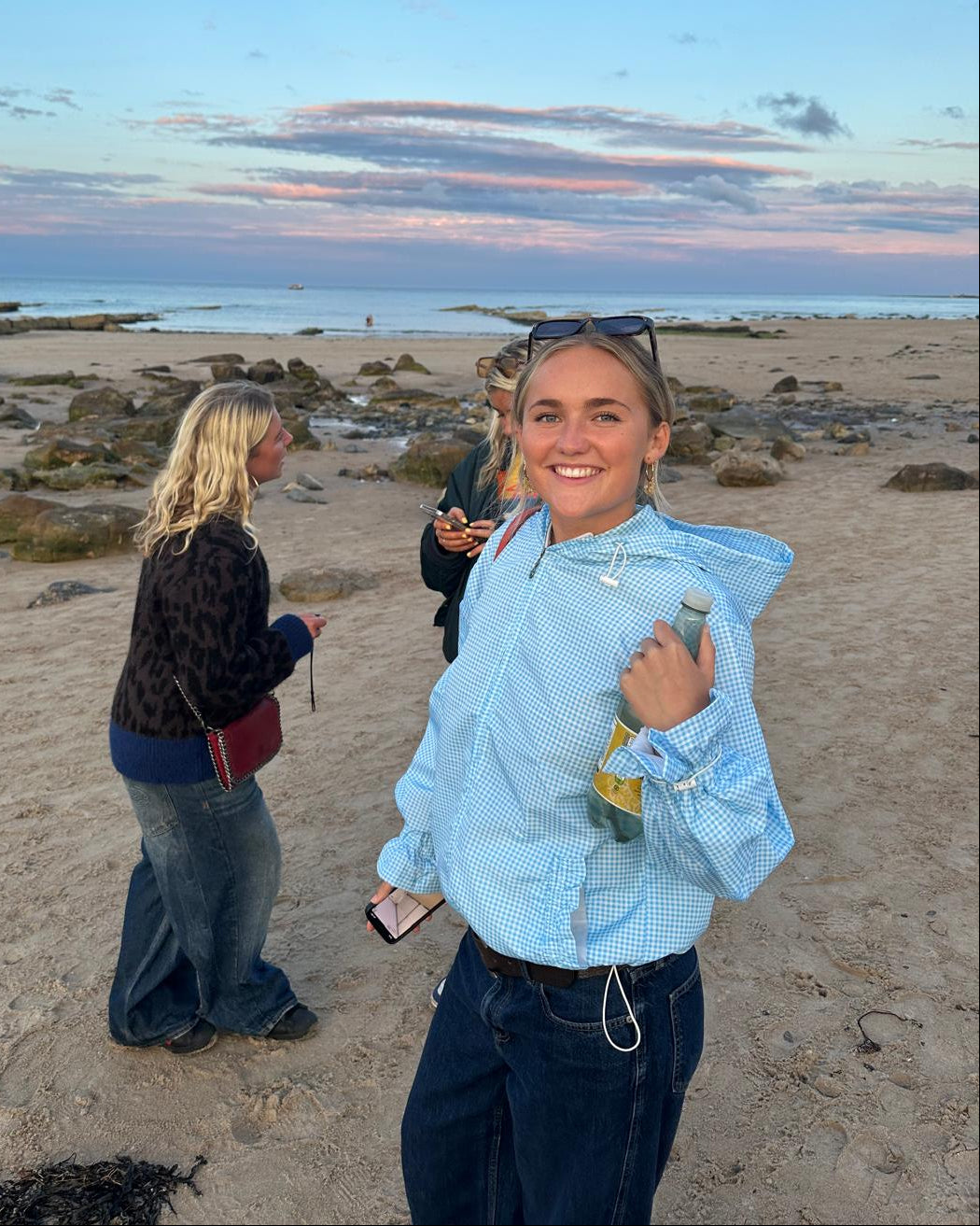 A women on a beach wearing a blue gingham flared windbreaker