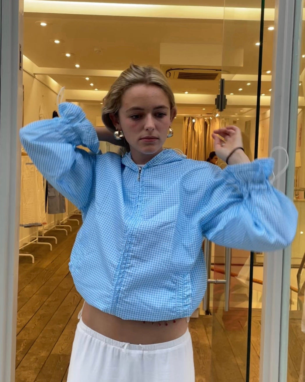 Person in a blue outfit walking on a city street with advertisements and traffic lights.
