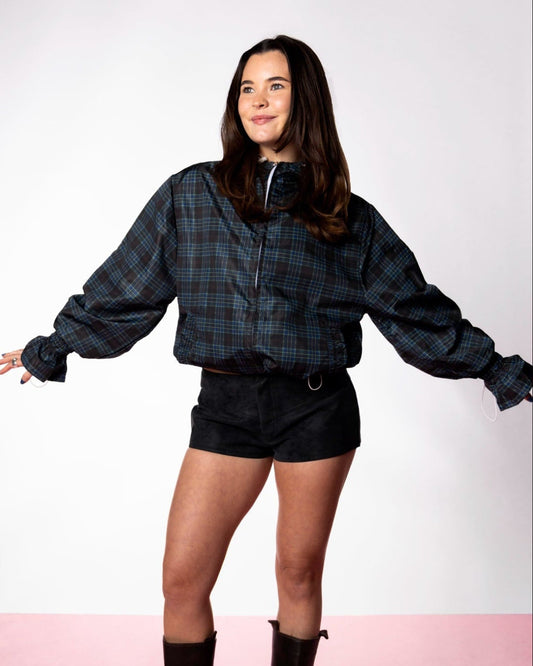 Person wearing a plaid shirt and black shorts on a white background