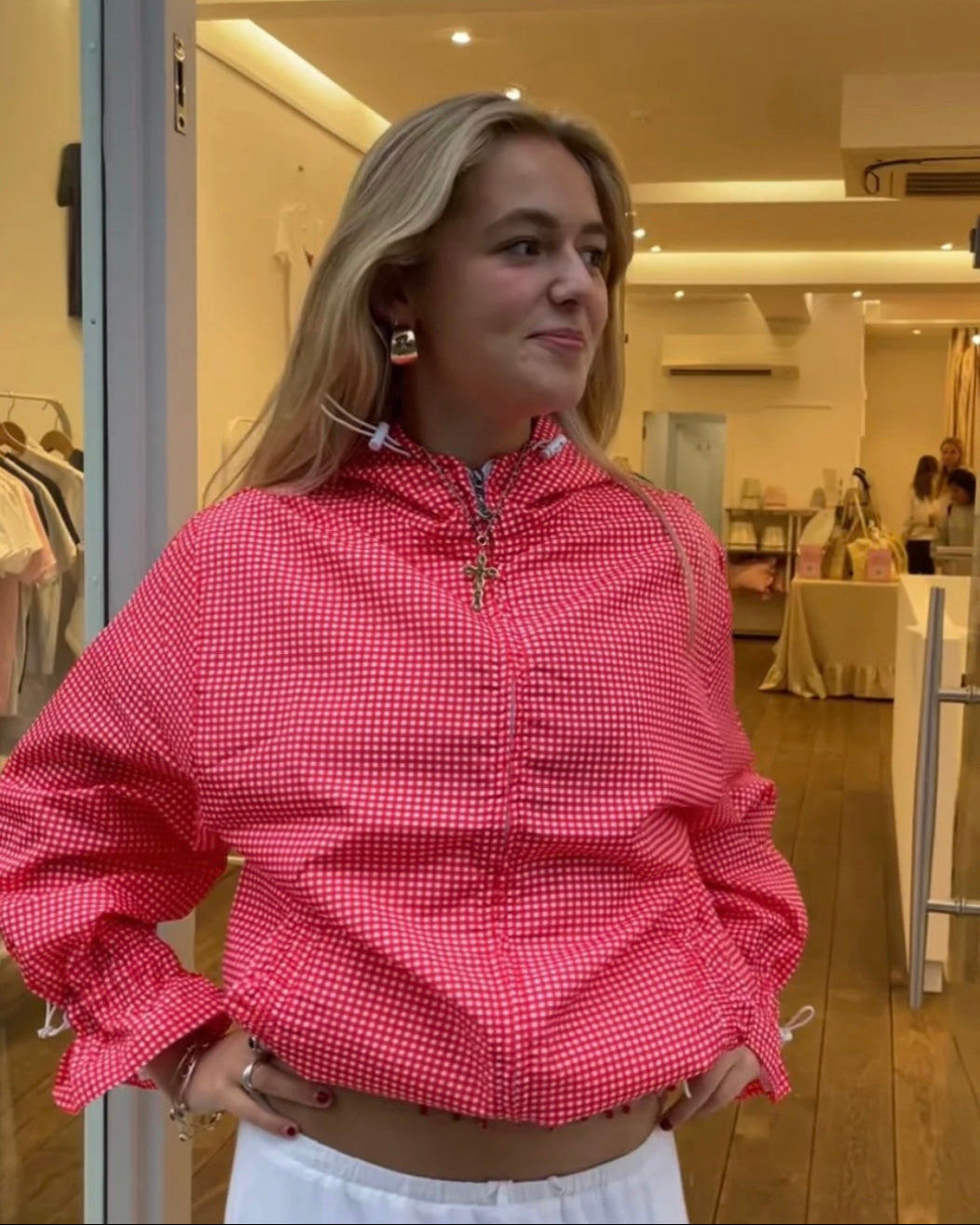 Woman wearing a red checkered windbreaker jacket in an indoor setting