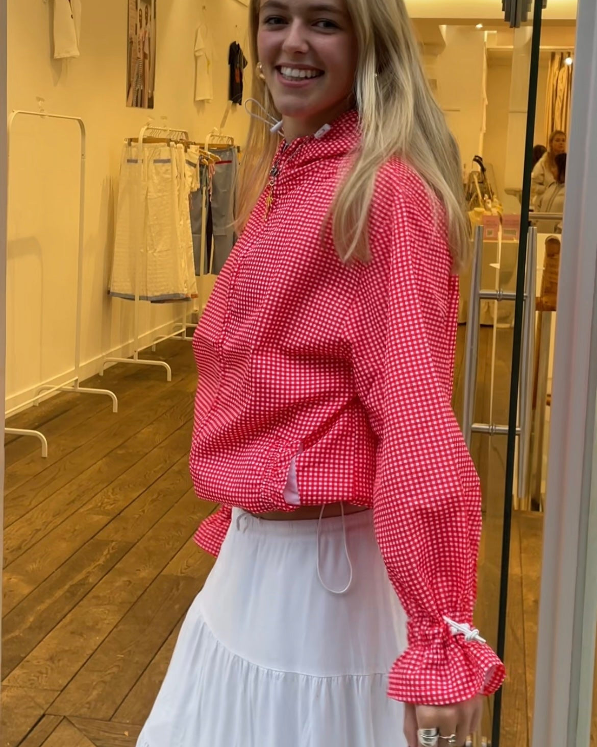 a woman wearing a red gingham windbreaker in a shop