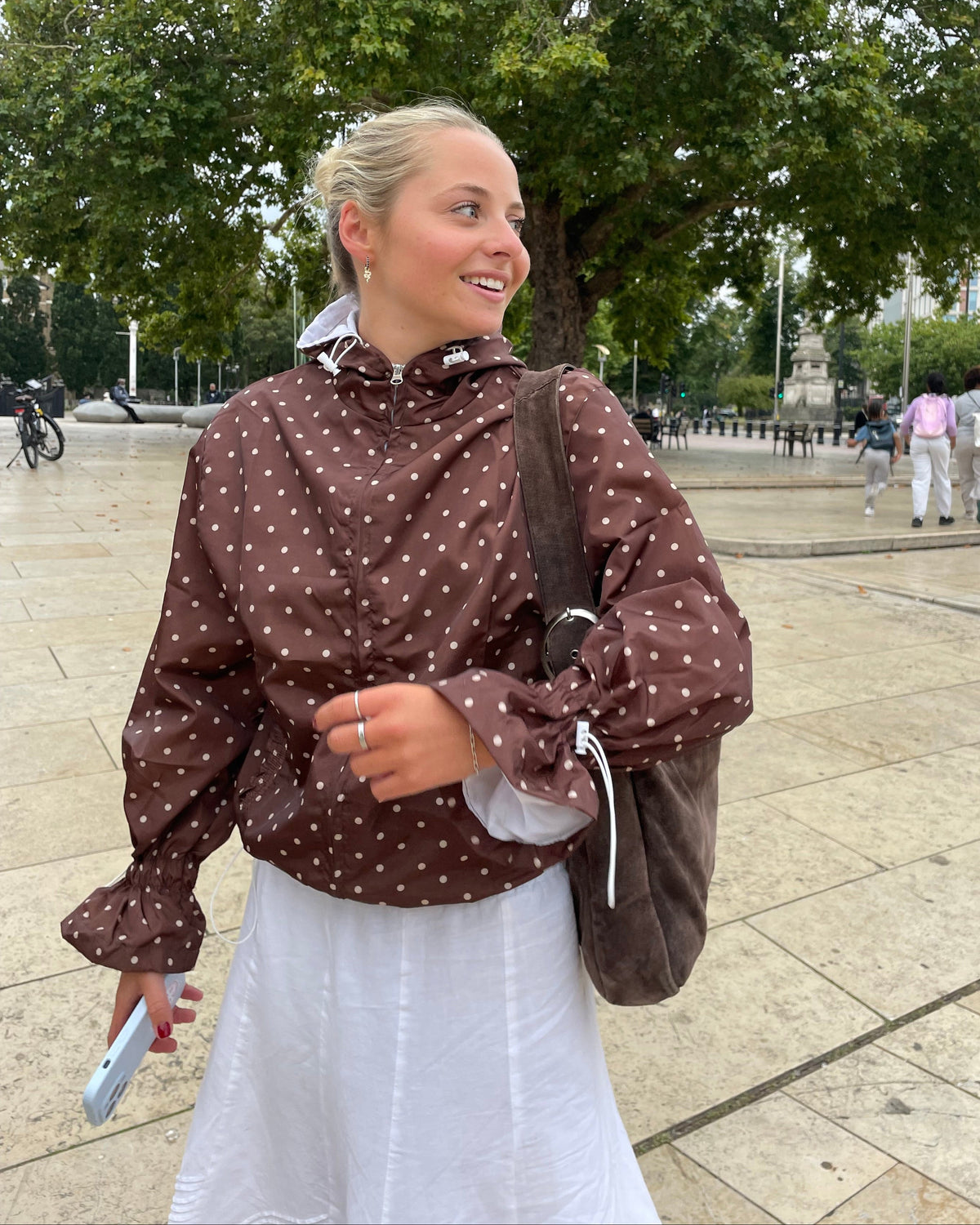 Person wearing a brown polka dot windbreaker with a white background