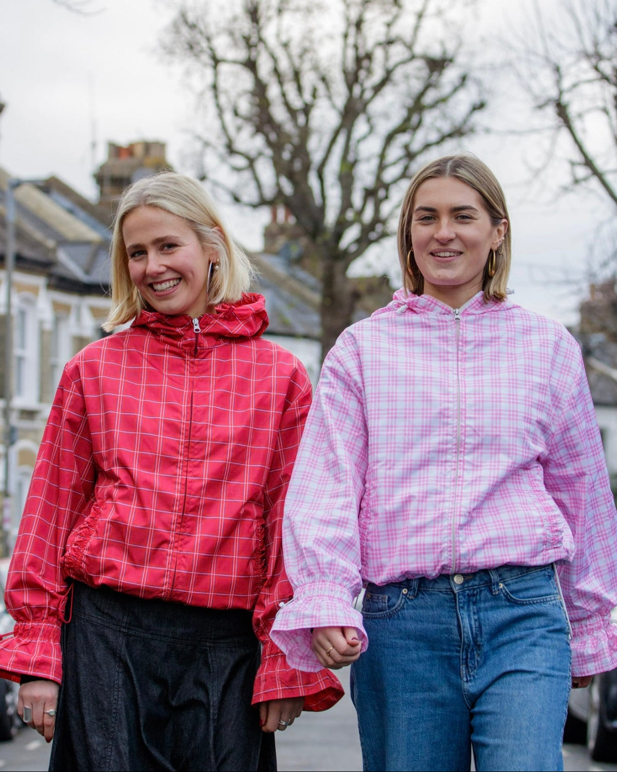 Two women wearing checkered jackets standing outdoors on a street.